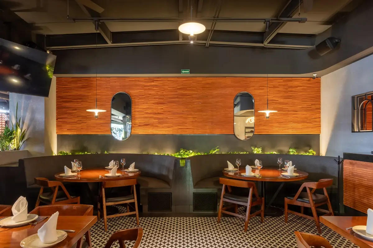 El comedor: madera cálida y penumbra íntima que alargan la sobremesa sin frenar el servicio.